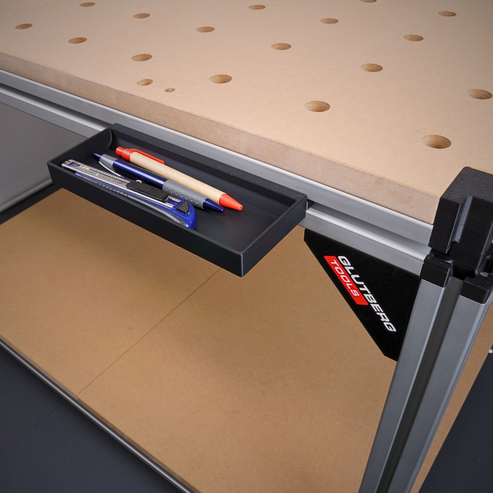 Werkzeugablage für die GLUTBERG Workstation Pro, am Aluprofil eingehängt und mit Stiften und Cuttermesser bestückt